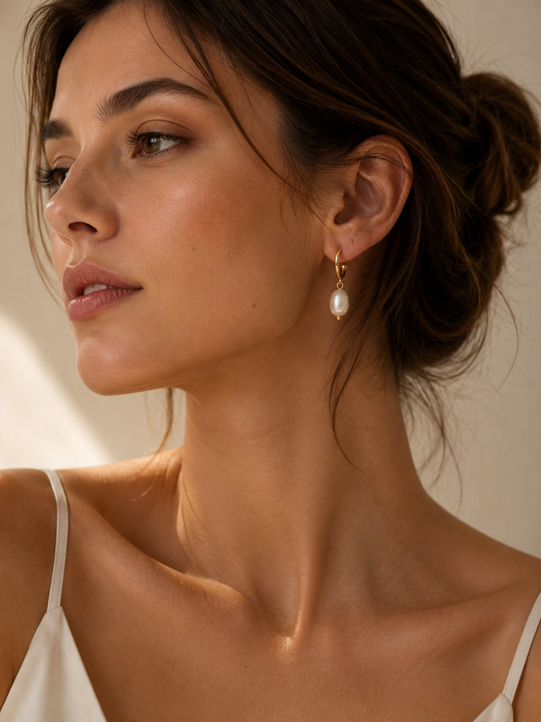 Woman wearing the Daphne Gold Pearl Earrings featuring genuine freshwater pearl drops on waterproof 18K gold PVD stainless steel hoops.