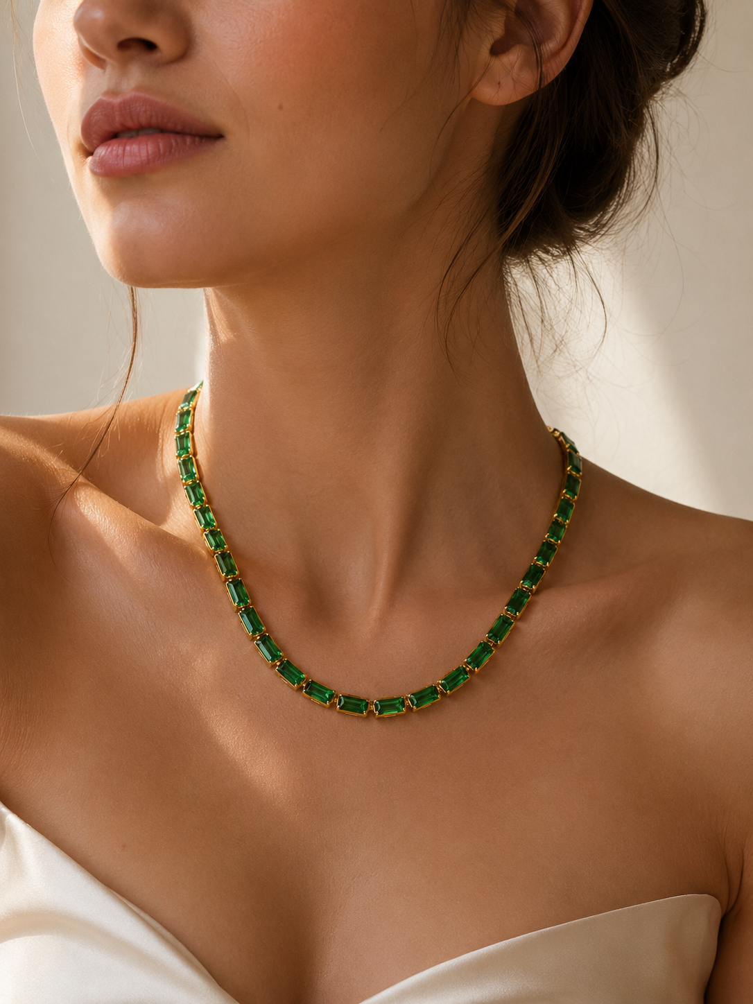 Woman wearing the Isadora Emerald Gold Necklace with emerald-cut green zircon stones and a gold finish.