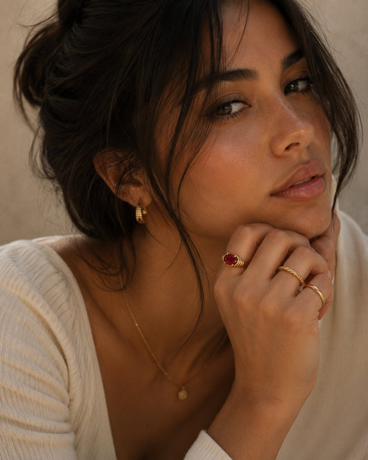 Woman wearing the Naomi Ring with a radiant red zircon stone in a gold PVD stainless steel setting by Maison Élyséa