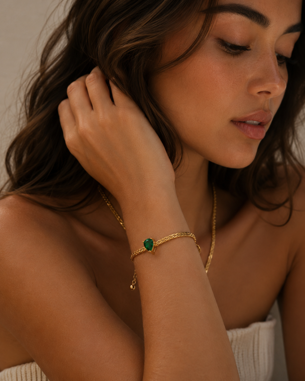 Woman wearing the Vivienne Gold Emerald Bracelet with a vibrant green heart-cut zircon stone by Maison Élyséa